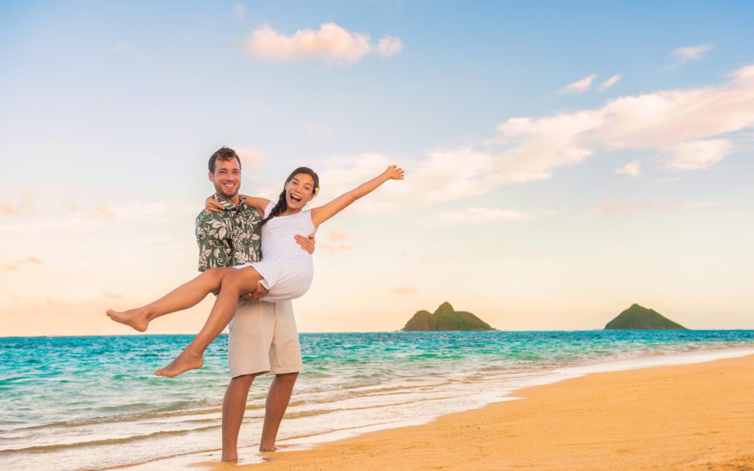 A happy couple stands on a beach in Hawaii